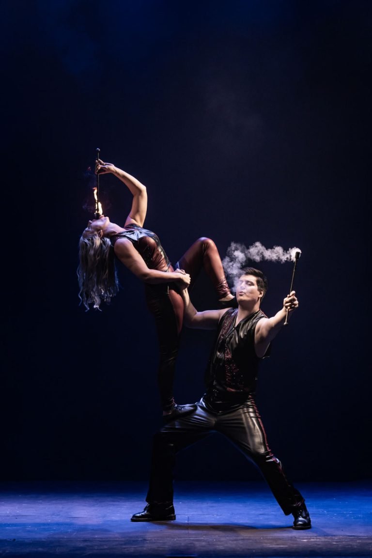 Two performers in an acrobatic pose eating fire